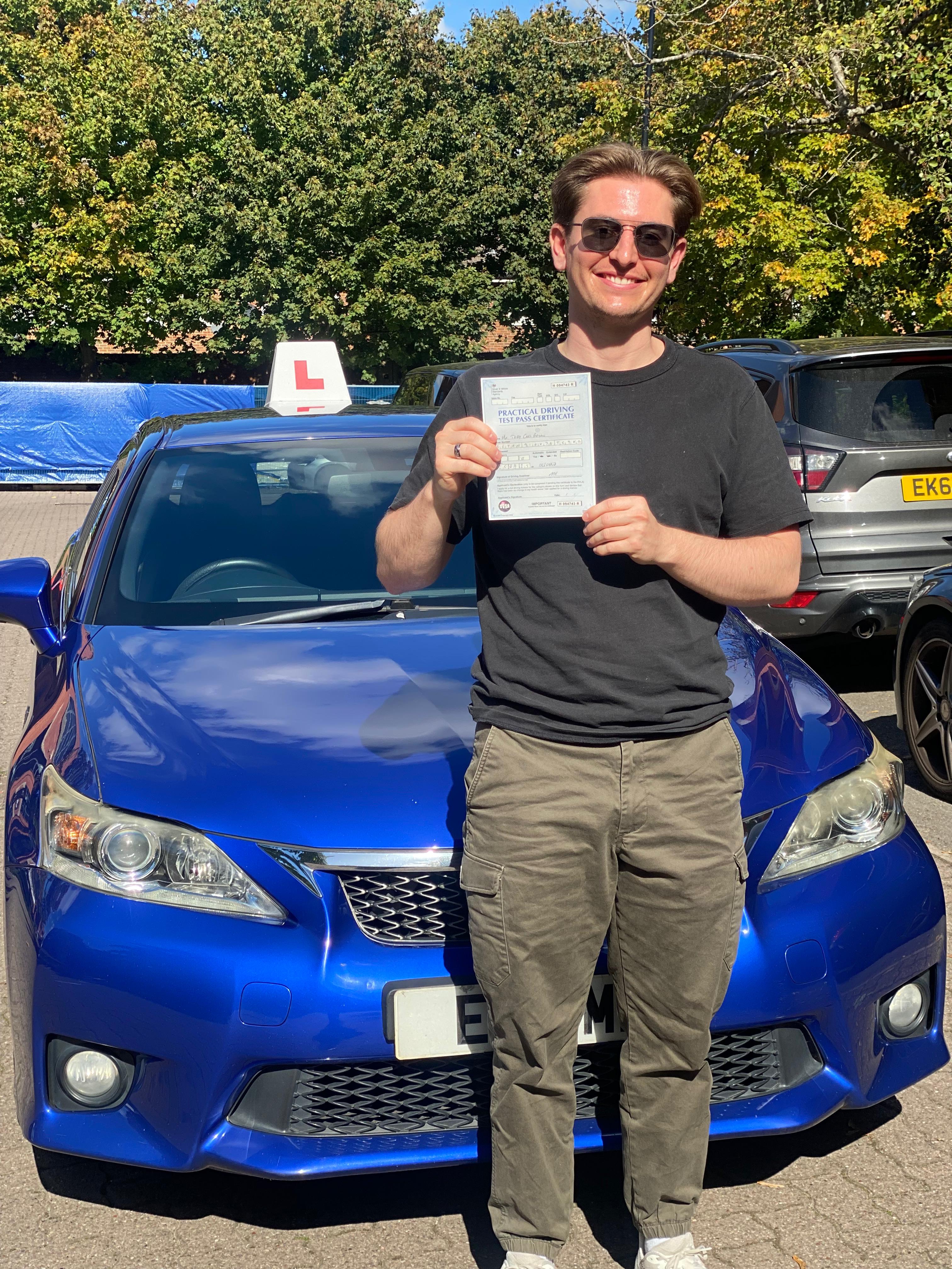 A happy learner holding their driving test pass certificate by the My First Drive car
