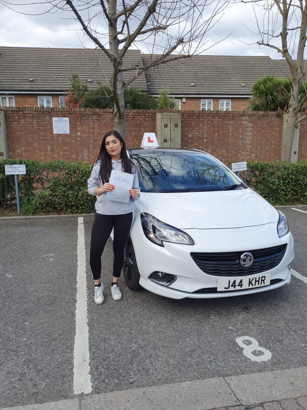 A happy learner holding their driving test pass certificate by the My First Drive car