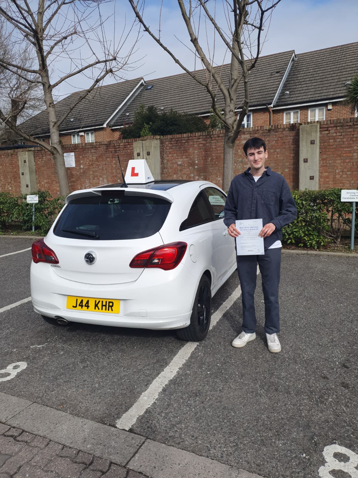 A happy learner holding their driving test pass certificate by the My First Drive car