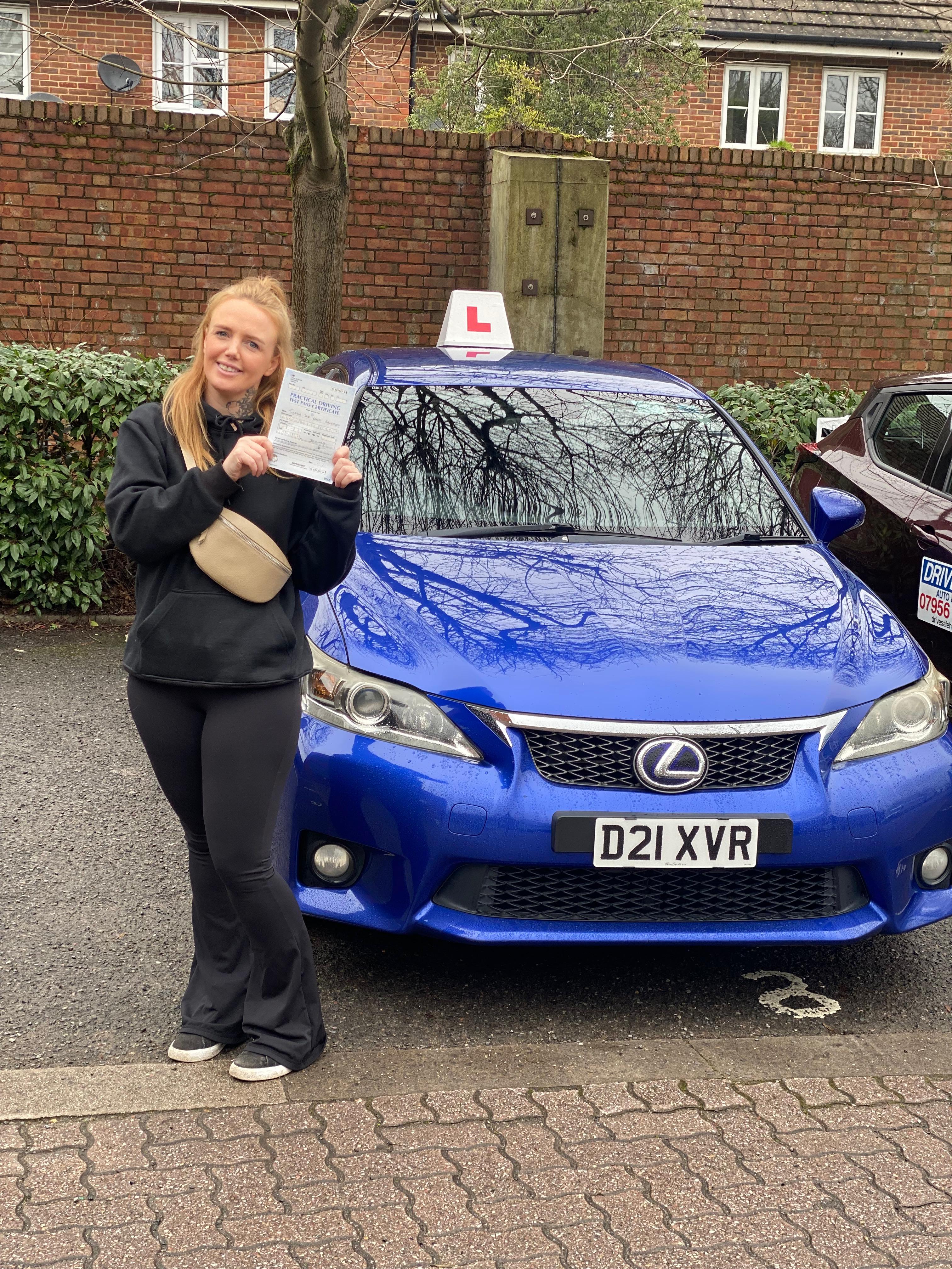 A happy learner holding their driving test pass certificate by the My First Drive car